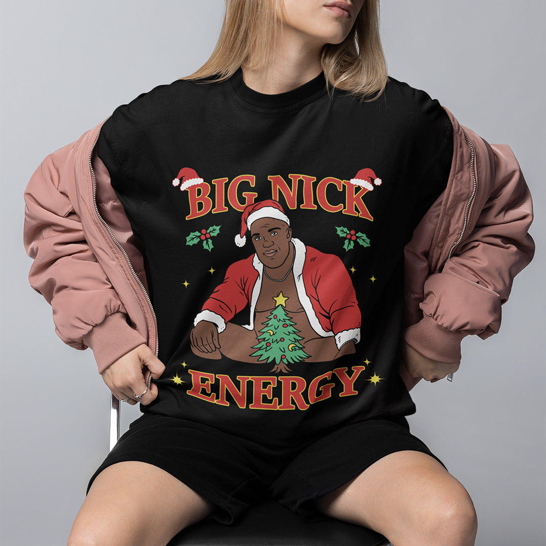 Model wearing an Orbital Clothing black t-shirt featuring funny Christmas graphic text Big Nick Energy with Santa Claus design