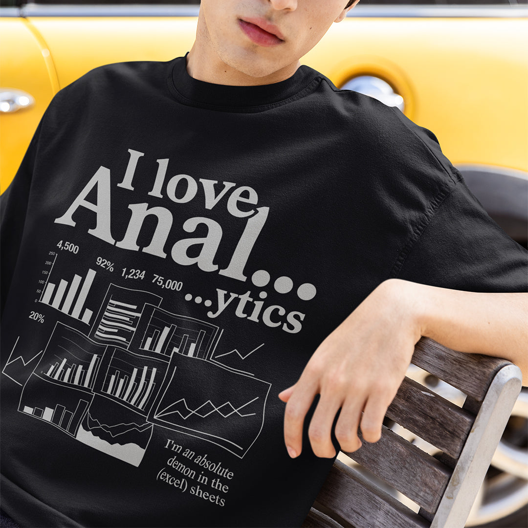 Person wearing a black t-shirt with graphic text and charts, sitting on a bench.