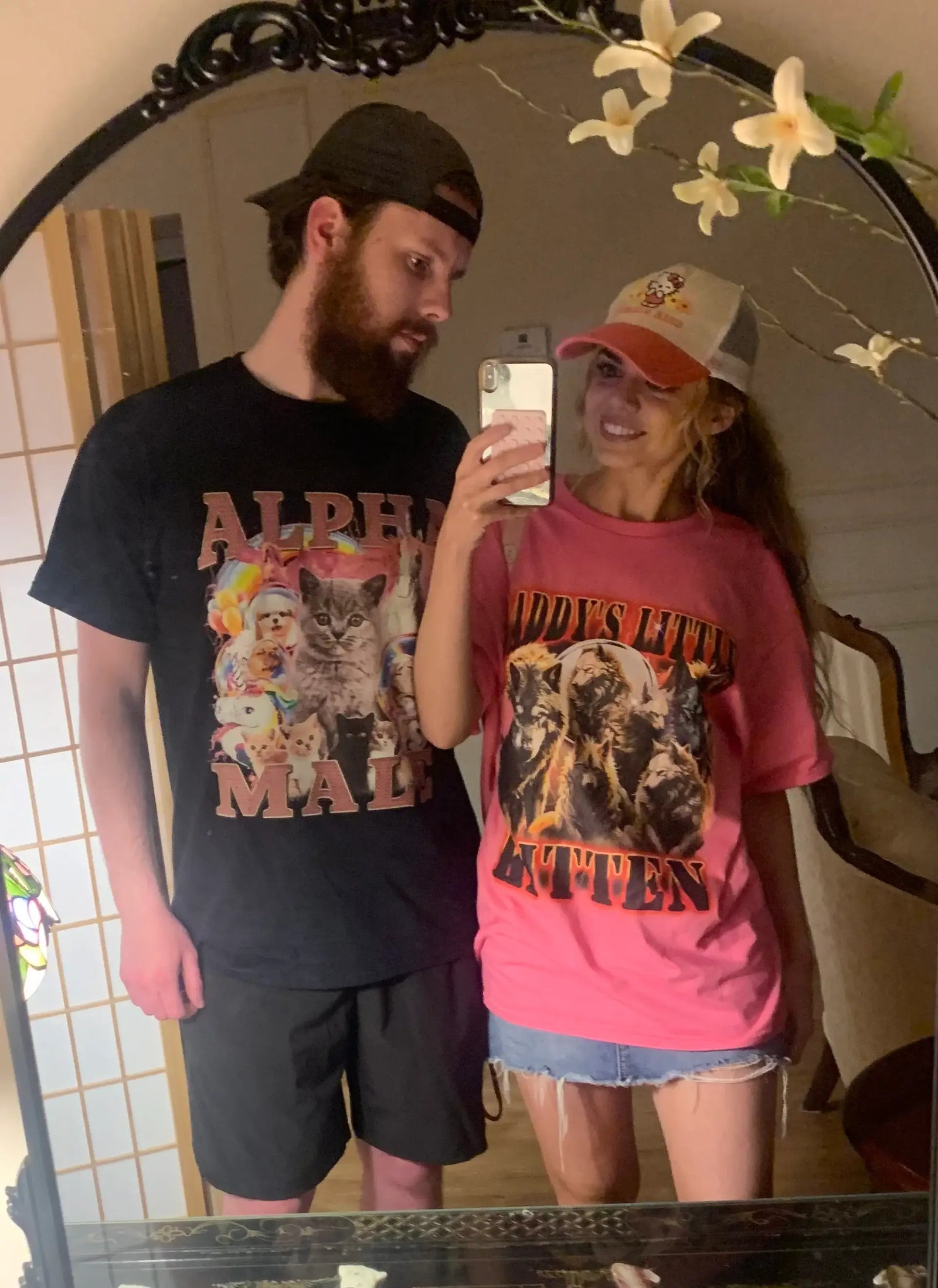 Couple wearing ironic matching tees: ALPHA MALE with cute cats and DADDYS LITTLE KITTEN with wolf pack.
