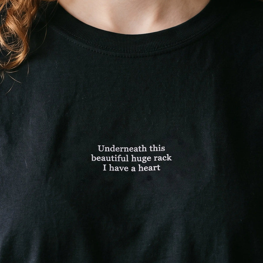 Underneath this beautiful huge rack I have a heart embroidered t-shirt in black, worn, close-up of the stitching
