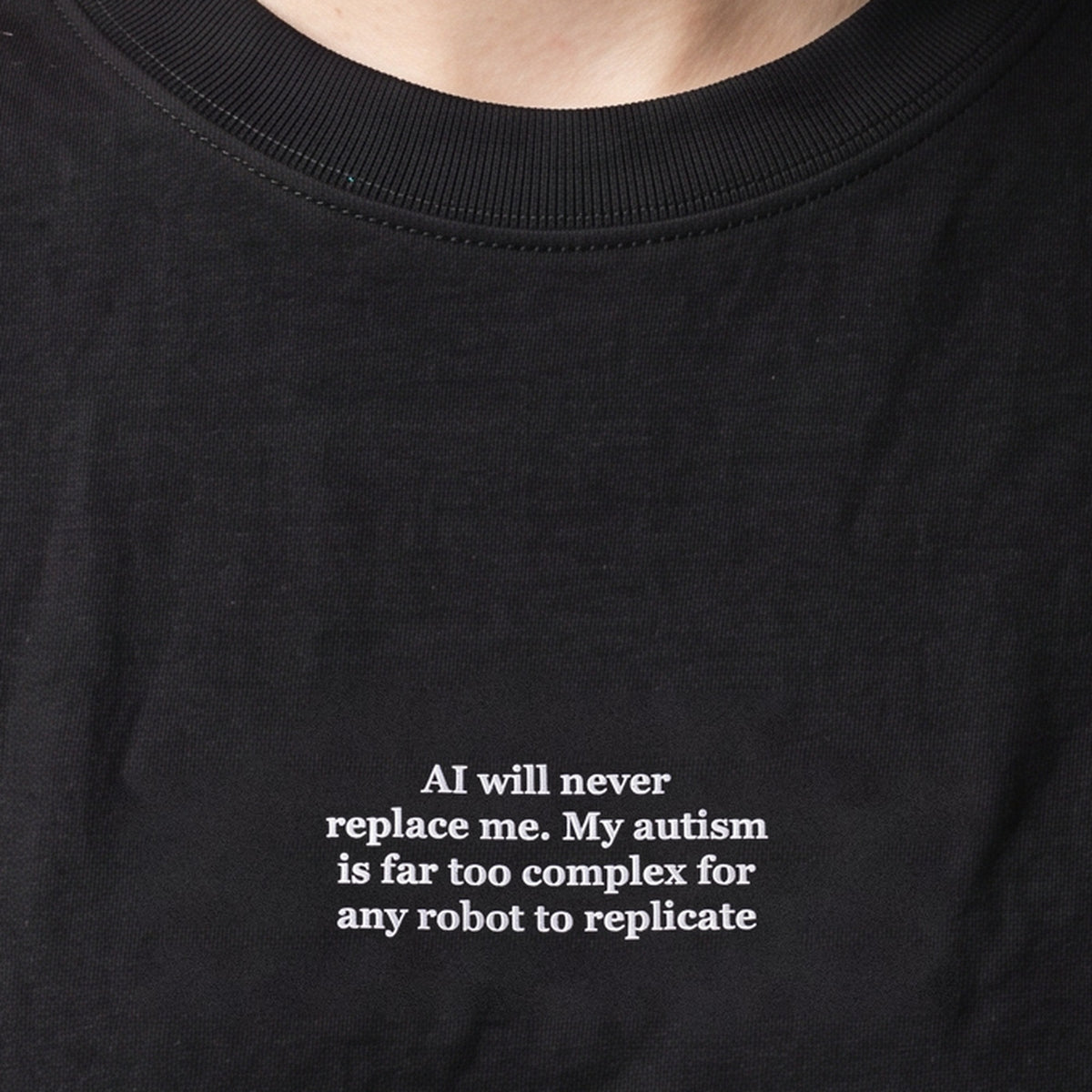 AI will never replace me. My autism is far too complex for any robot to replicate (embroidered) T-Shirt in black, worn, close-up of the stitching