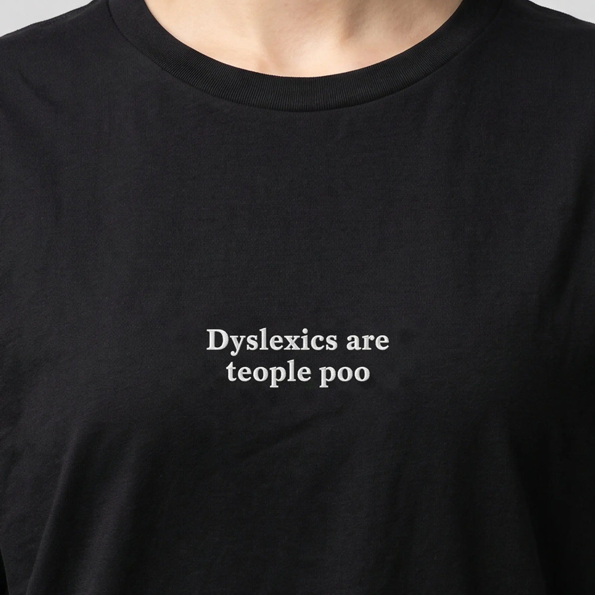 Dyslexics are teople poo embroidered t-shirt in black, worn, close-up of the stitching