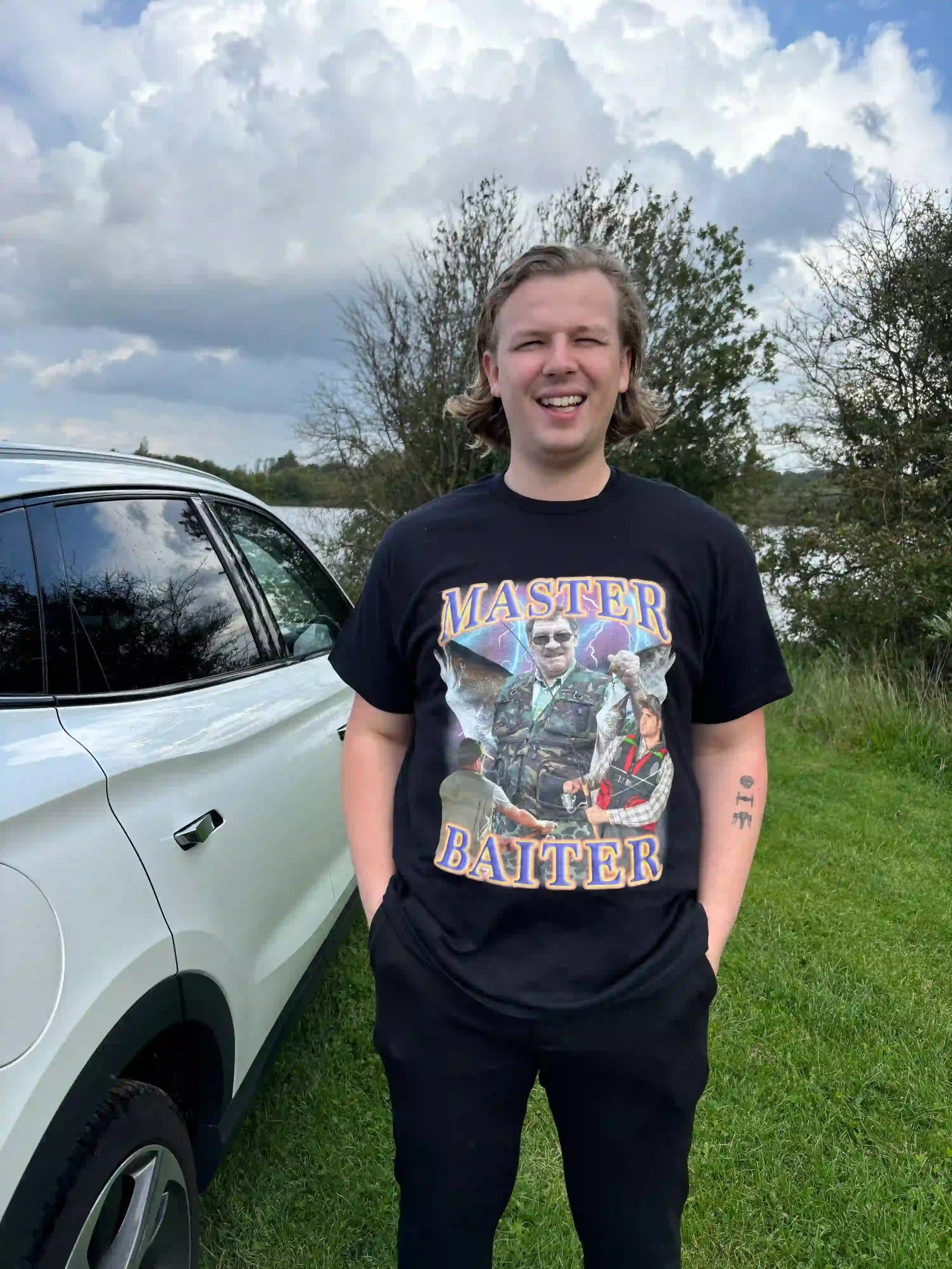 Man wearing a black t-shirt with a retro fishing graphic and the pun text MASTER BAITER.