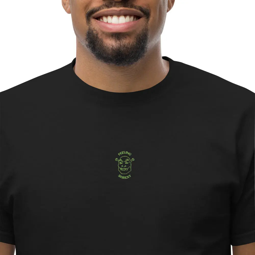 Close-up of the Feeling Shrexy green embroidery on the chest of a black premium t-shirt